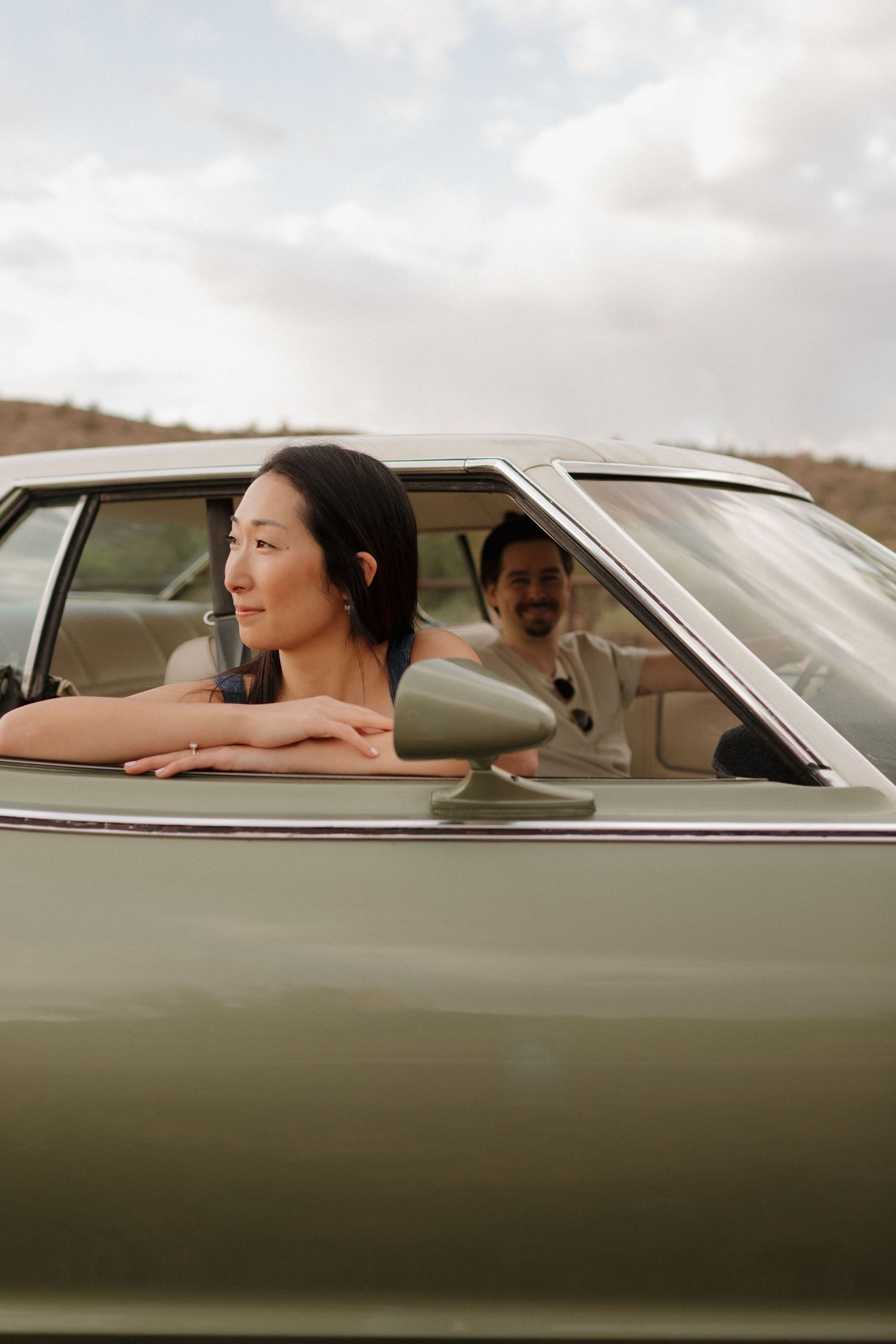A vintage car ride capturing a candid moment through the driver's side window at sunset.