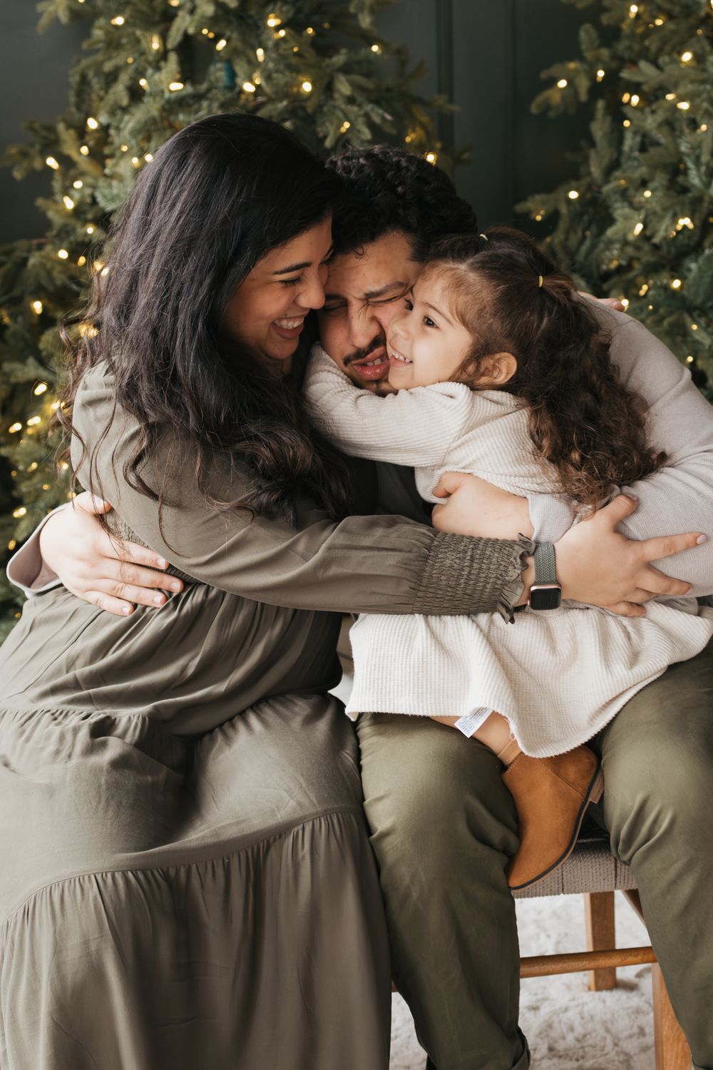 A tender family moment shared in front of a glowing Christmas tree with warm embraces.
