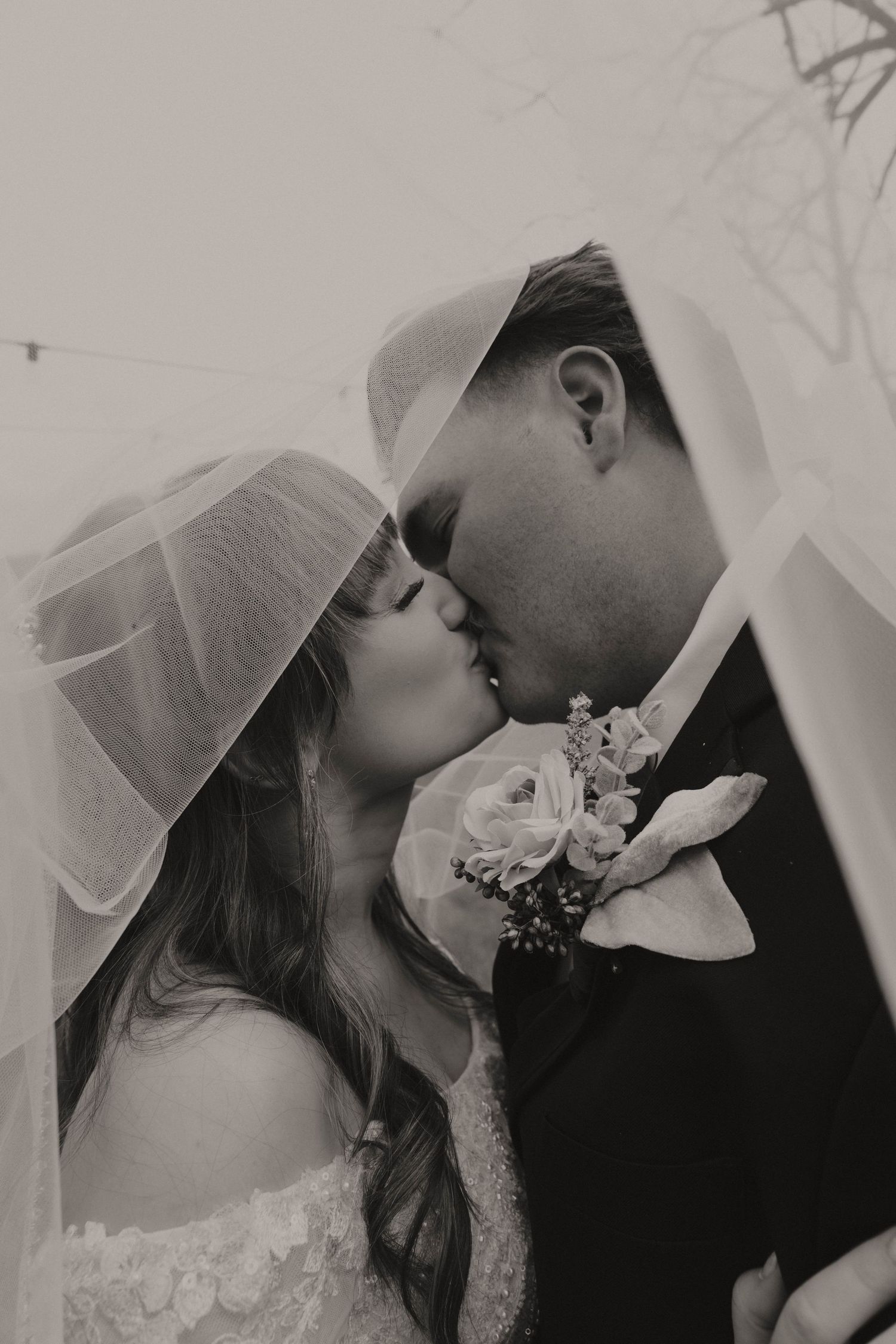 A romantic wedding moment captured in black and white with a corsage and veil.