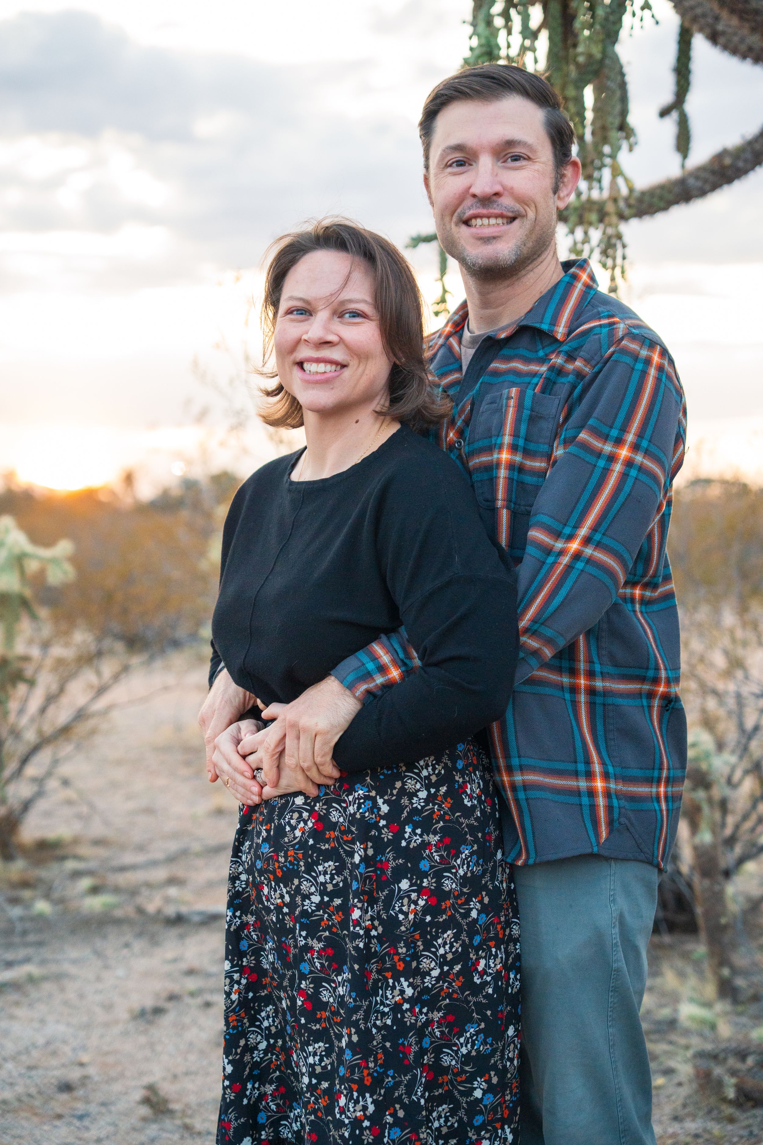 A couple embraces while posing for a portrait in the desert during golden hour. arizona phtography adventure engagement photographer