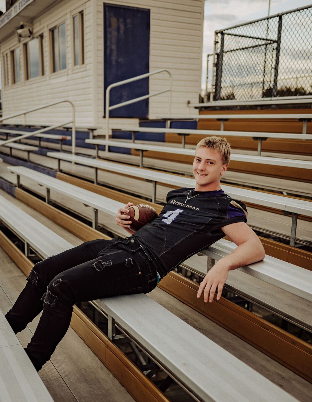 Football player figure relaxing on bleacher seats in uniform.  Senior football pictures. Senior pictures.