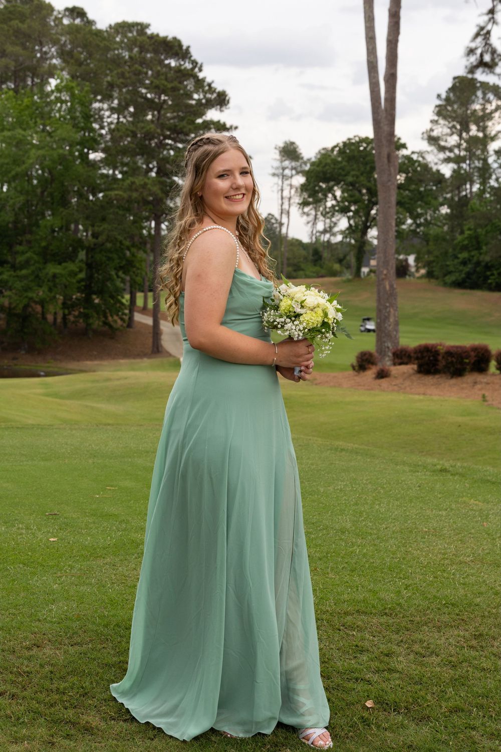 A sequence of photos showing someone in a flowing sage green bridesmaid dress posing gracefully on a lush golf course lawn.