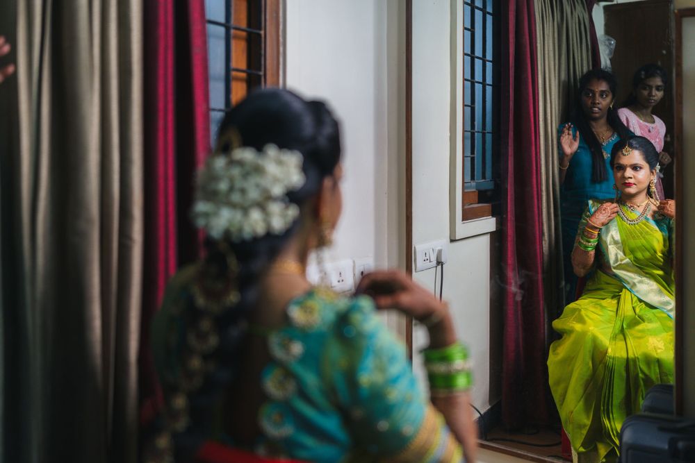 People in traditional South Indian attire prepare for a wedding ceremony inside a hallway with curtains.