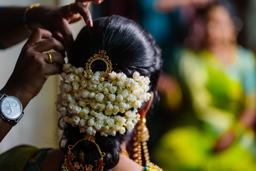 Close-up shot of traditional Indian bridal hairstyling with pearl accessories and golden ornaments being arranged.