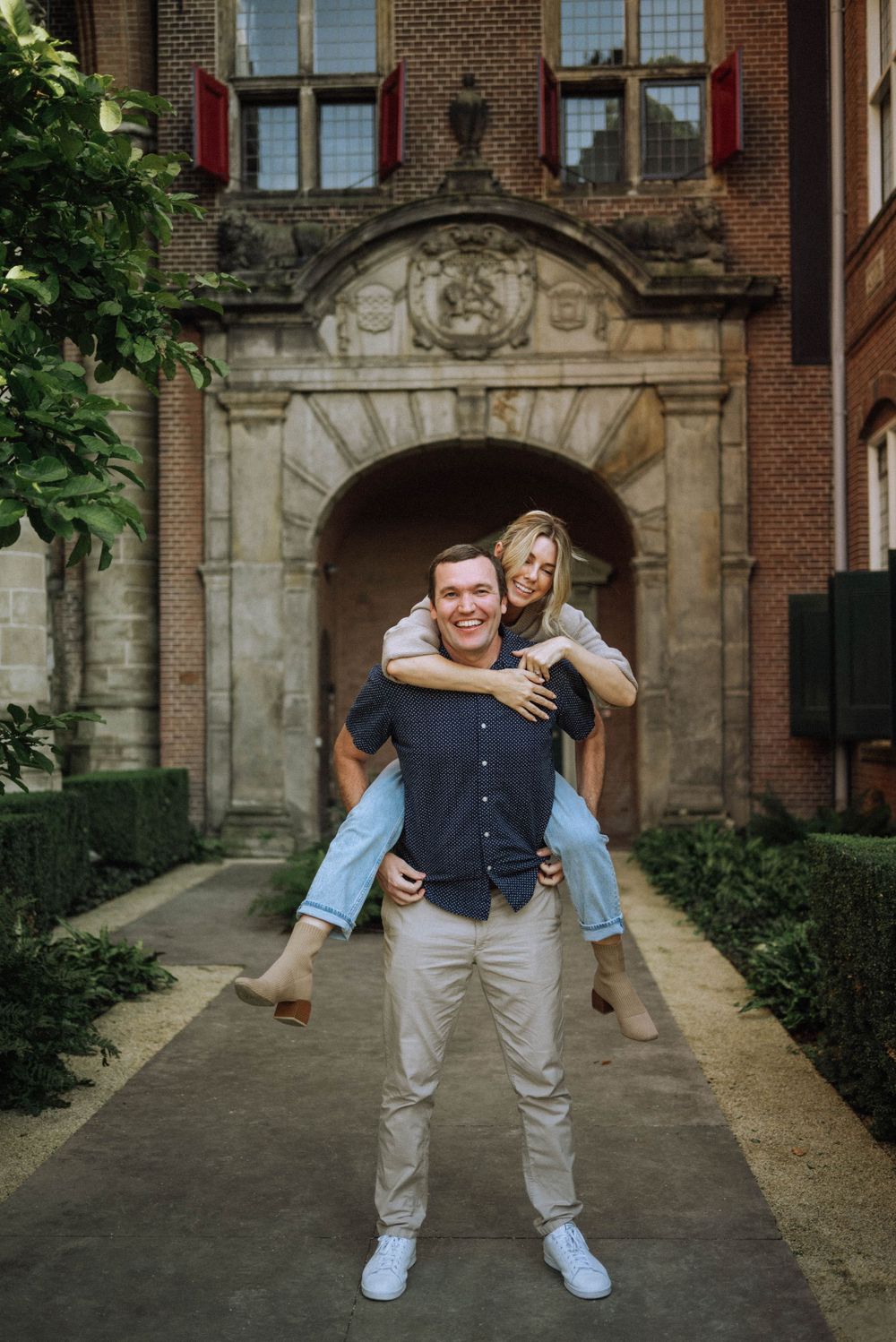 Playful couple sharing a fun moment in front of a decorative stone archway.