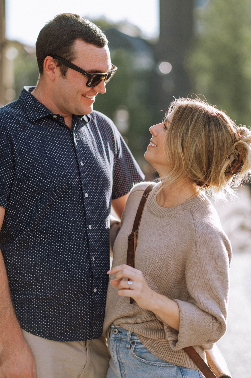 Couple in casual attire sharing a romantic moment outdoors on a sunny day.