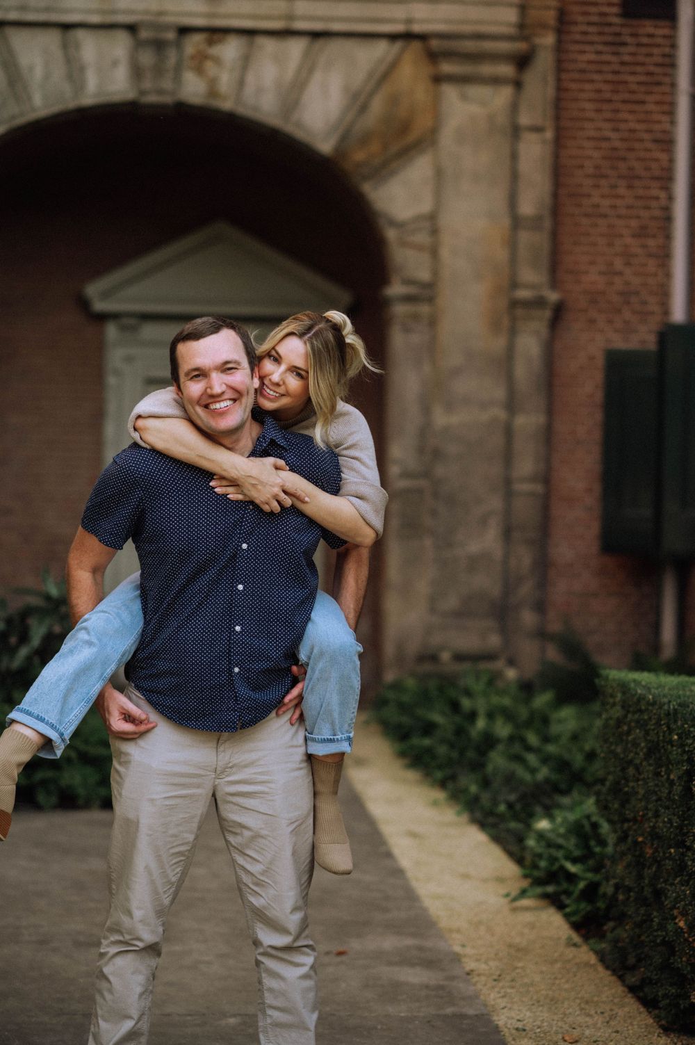 Playful piggyback ride moment in front of historic brick building.