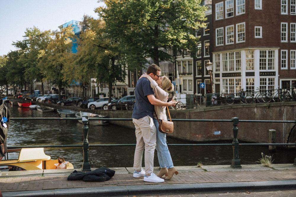 Waterfront view of Amsterdam canal with people walking along the edge.