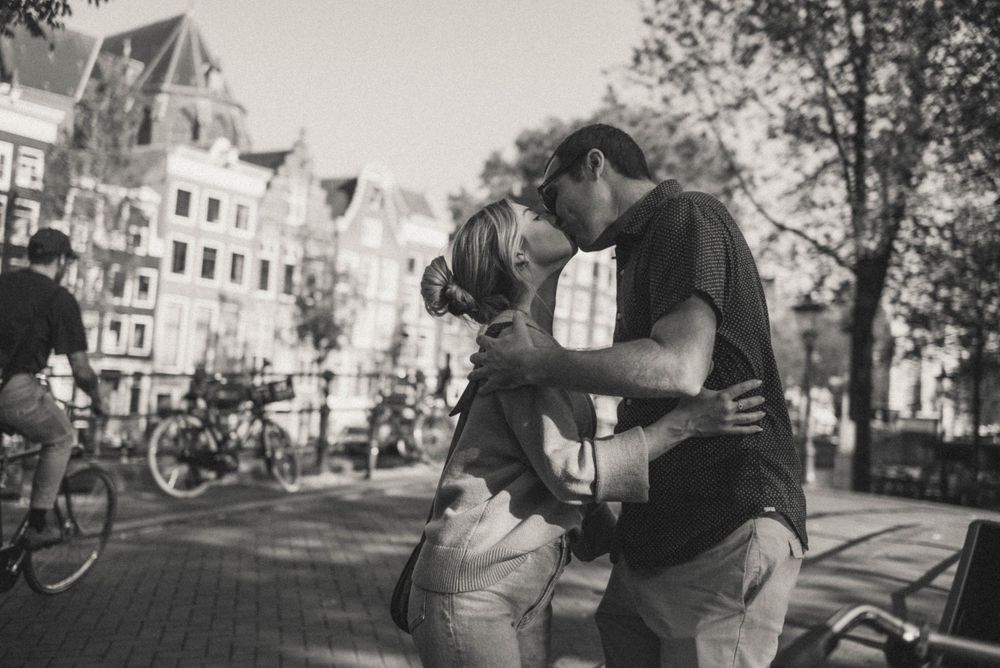Black and white photo of a couple sharing an intimate moment along an Amsterdam waterway.