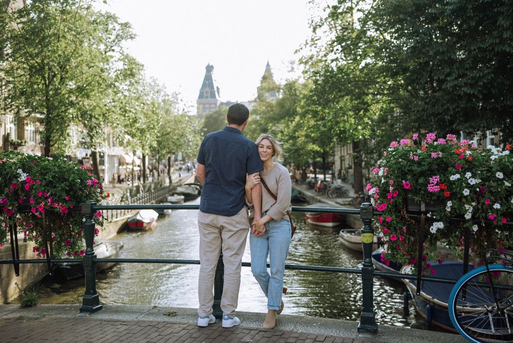 Romantic scene along Amsterdam's canals with flowers and historic architecture in the background.