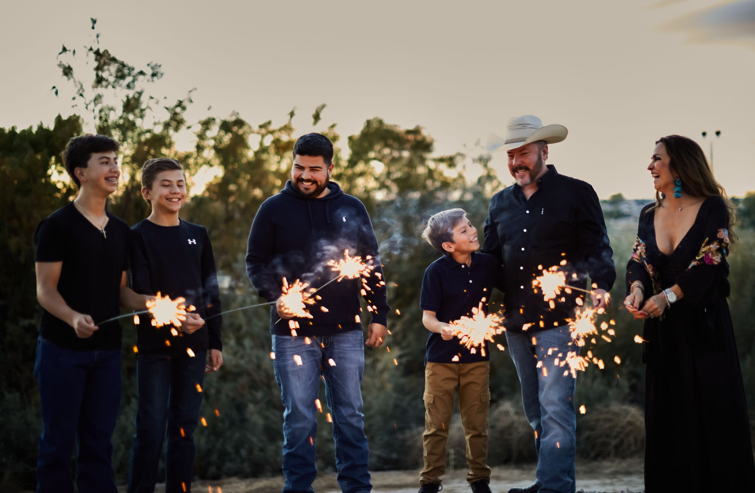Group of friends holding sparklers at dusk creating festive outdoor atmosphere.