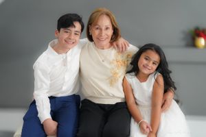 Three people pose together in a casual family portrait against a grey studio background.