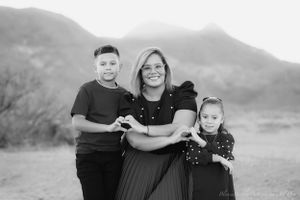 A family of three poses together against a mountain backdrop in black and white.