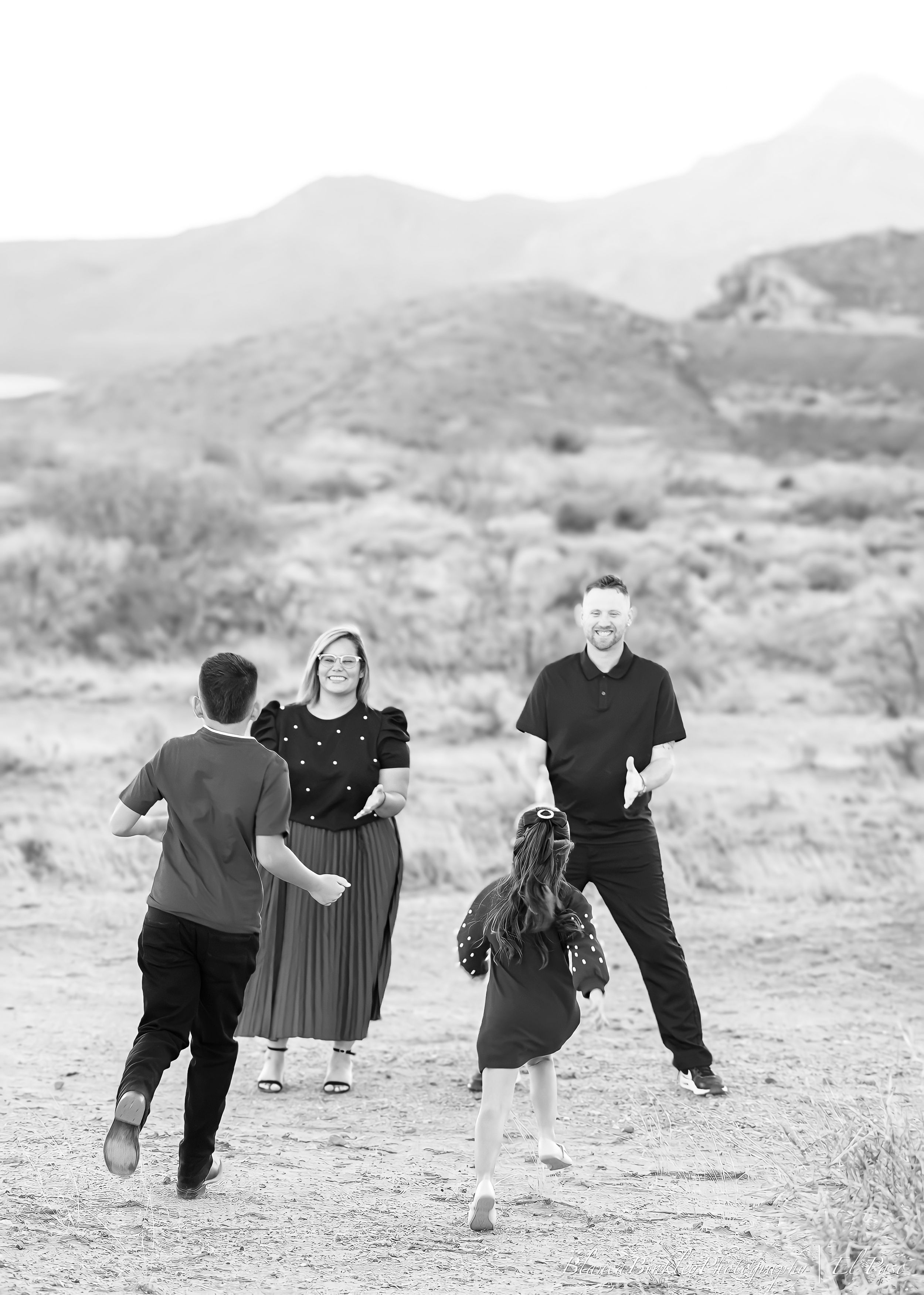 A family plays and runs together in a desert landscape setting.