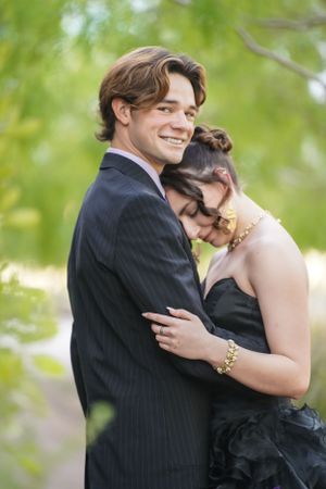 A tender moment between a couple in formal wear embracing outdoors.