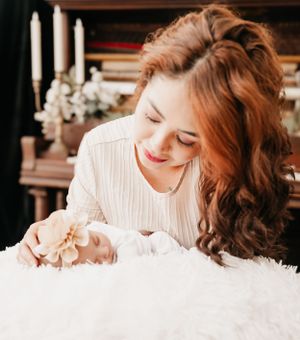 A joyful moment with someone looking down at something on a white fuzzy surface, with candles and flowers in the background.