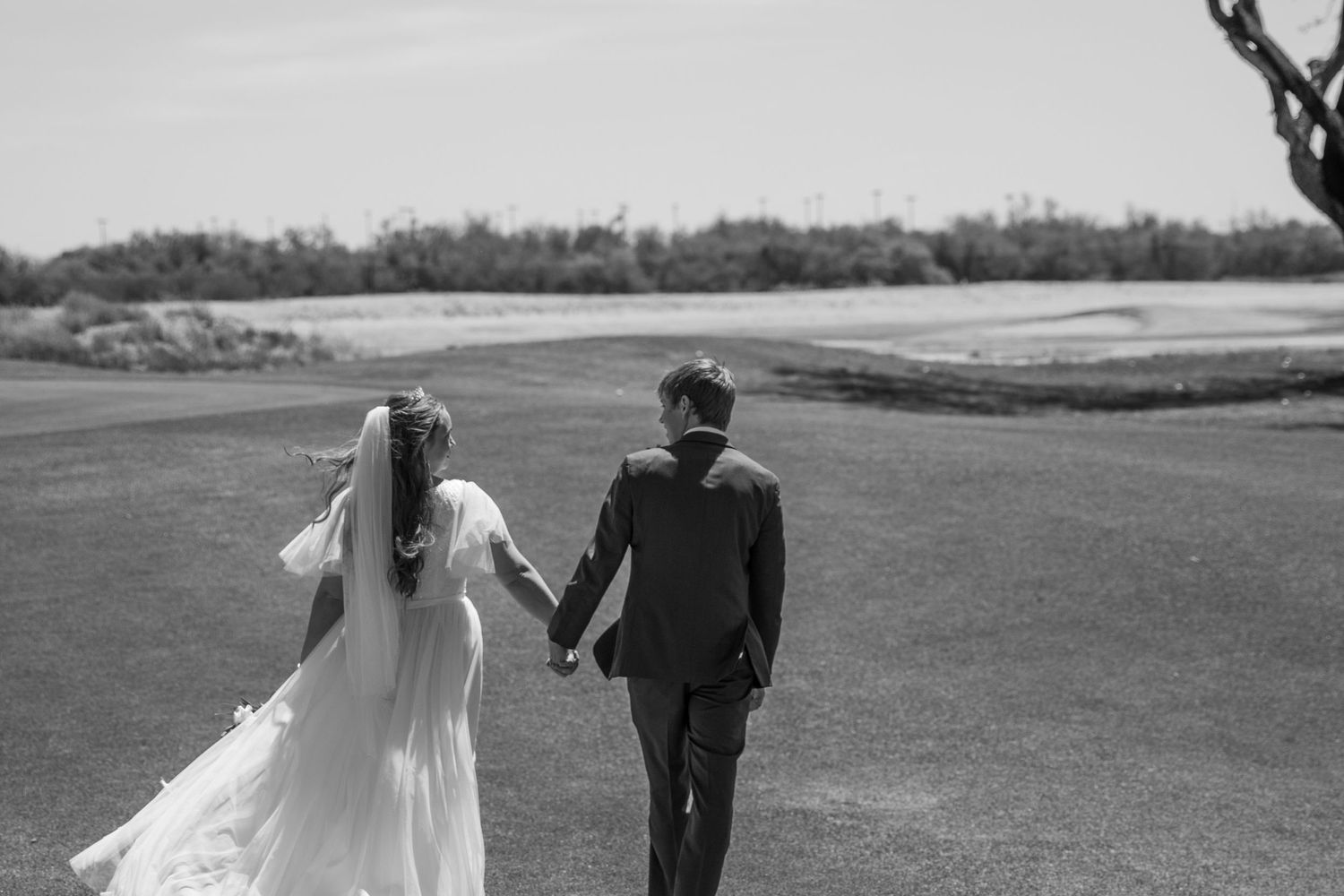 wedding-couple-walking-through-grassy-field-holding-hands