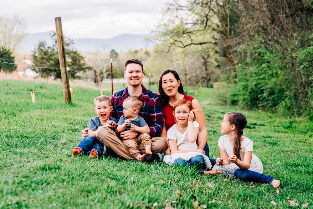 Photo of a family sitting on the lawn at a farm for a lifestyle family portrait session in Dandridge by family portrait photographer