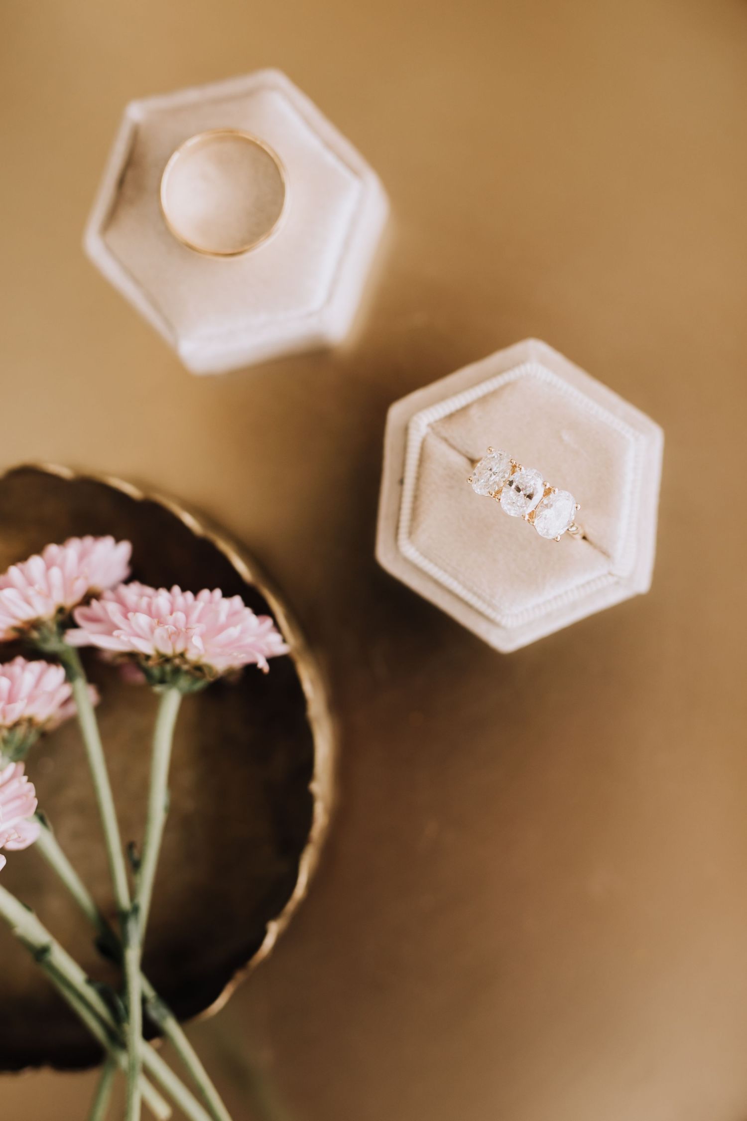 Diamond engagement ring in white hexagonal ring box with pink carnations in moody brown toned photography.