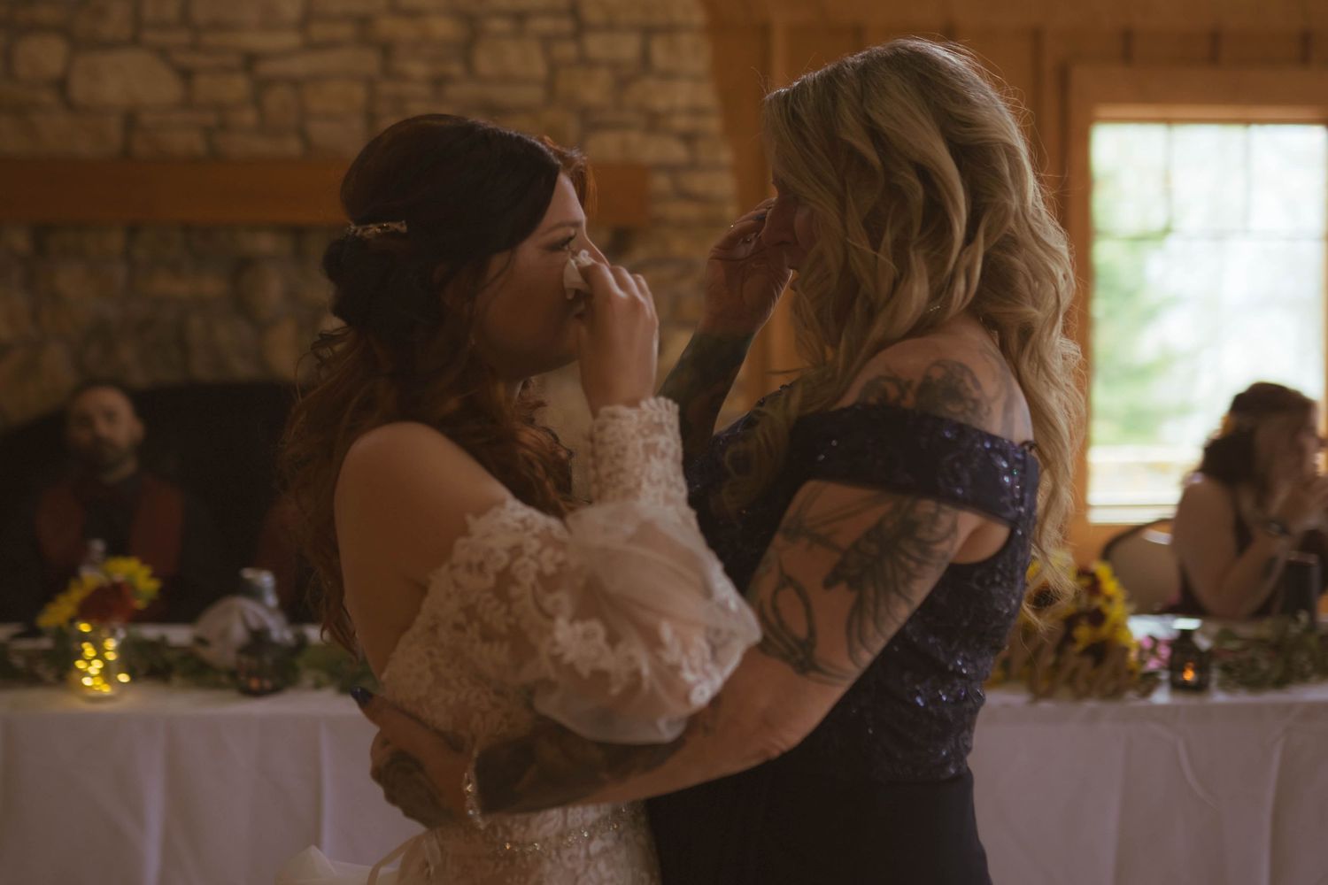 Wedding reception in a rustic brick venue with warm lighting and floral centerpieces.