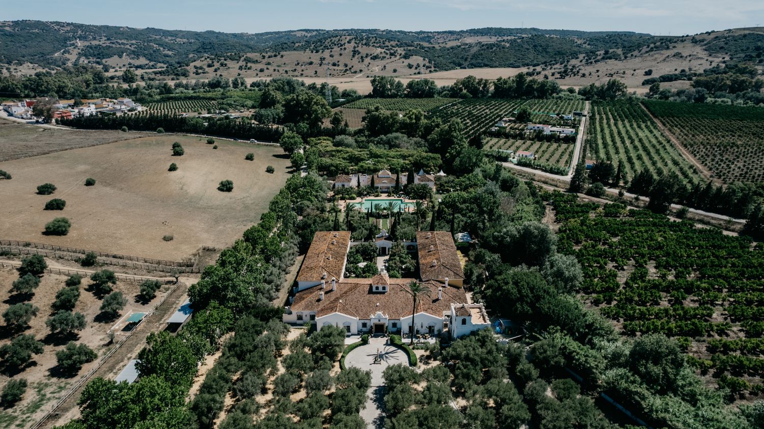 Aerial drone shot of a Mediterranean villa estate surrounded by vineyards and olive groves.