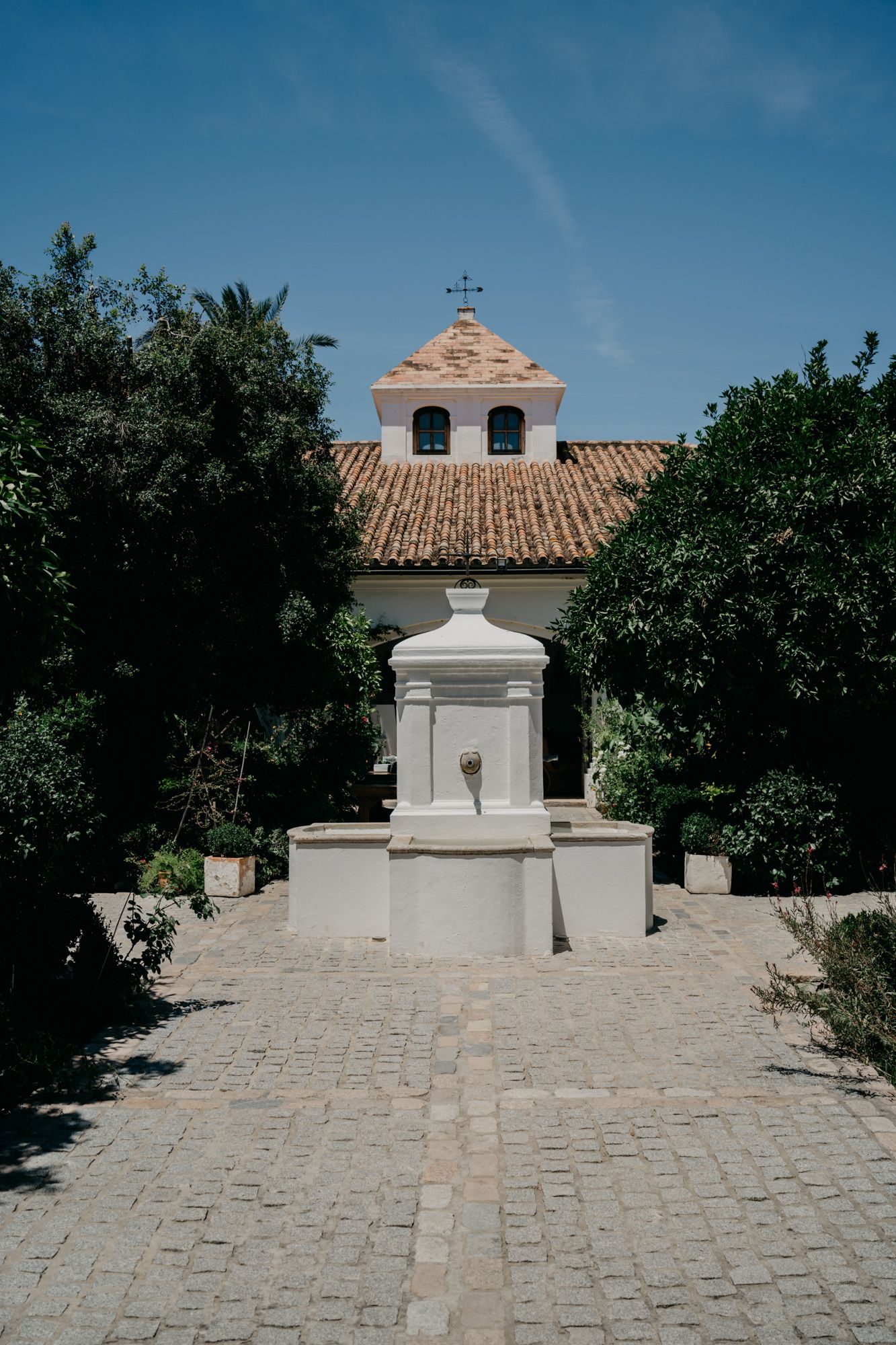 White chapel entrance with cobblestone path and traditional Mediterranean architecture.