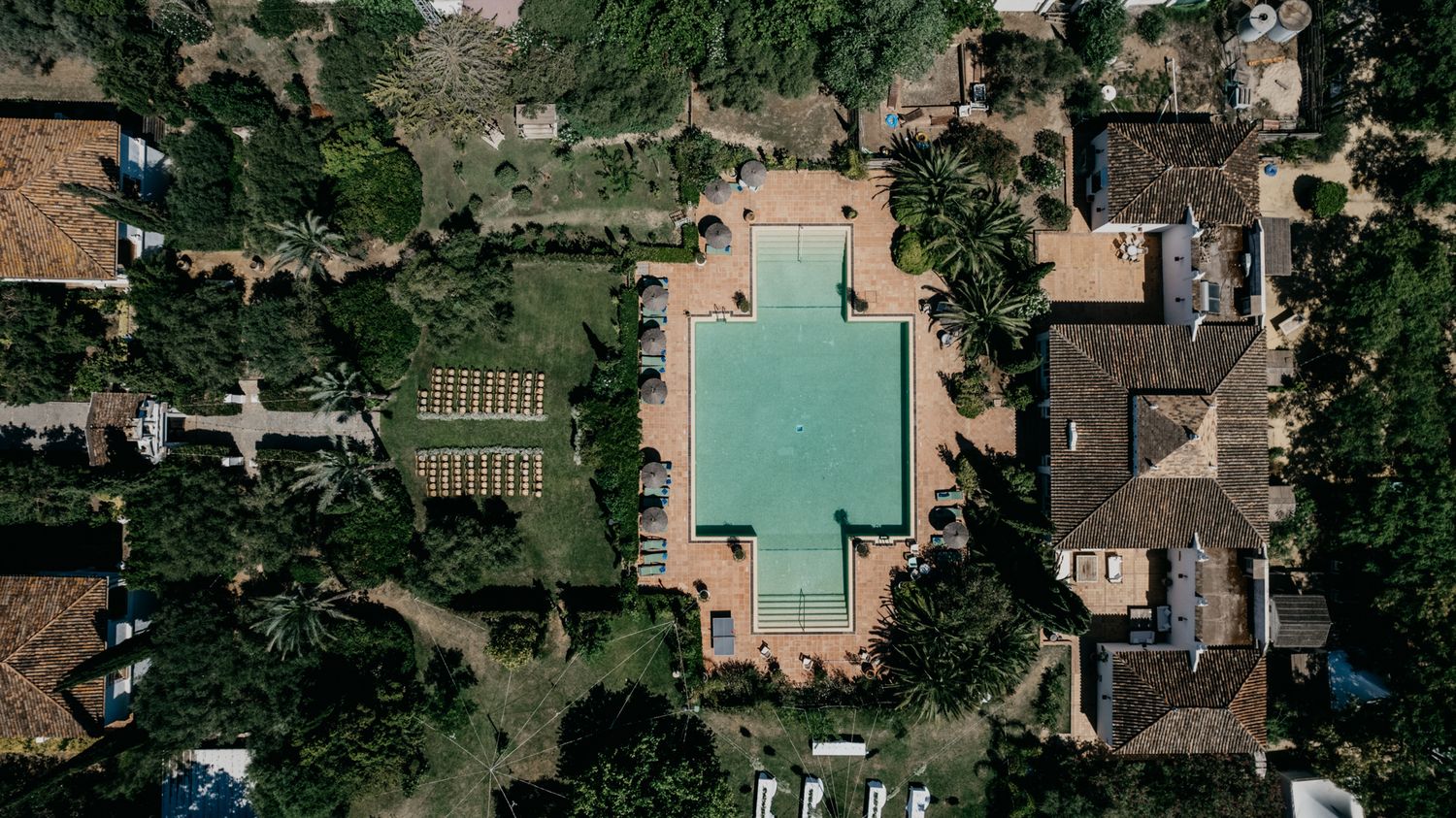 Bird's eye view of a luxury villa with turquoise pool and manicured gardens.
