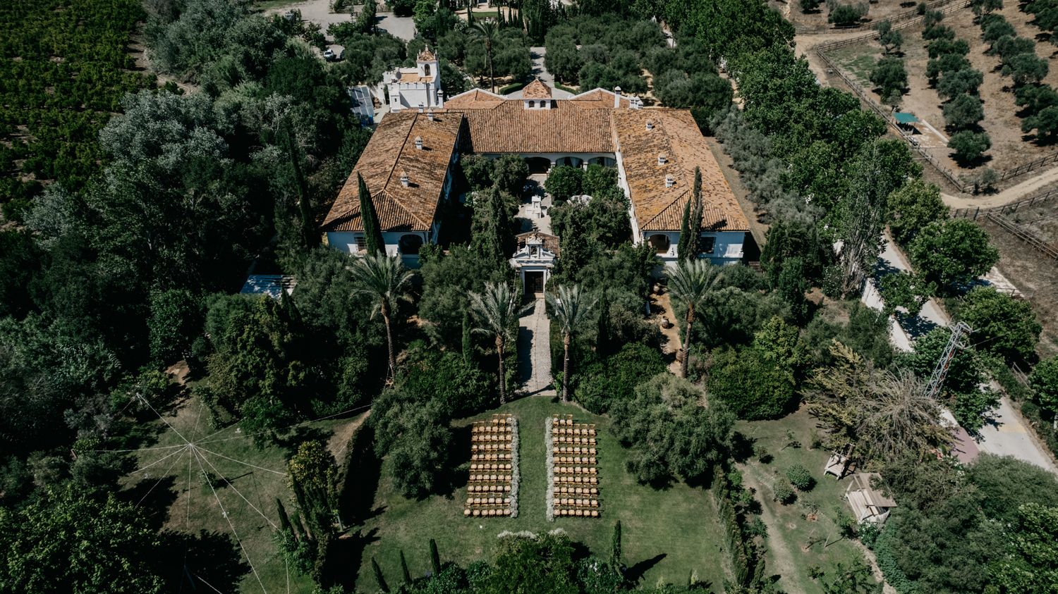 Aerial view of an elegant estate with symmetrical garden layout and ceremony setup.