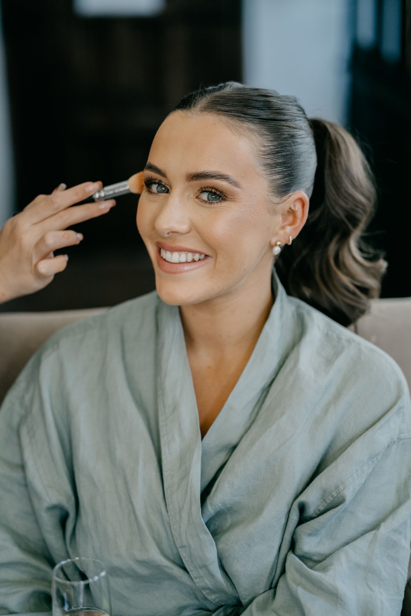 Getting ready shot of bridal makeup application in soft natural light.