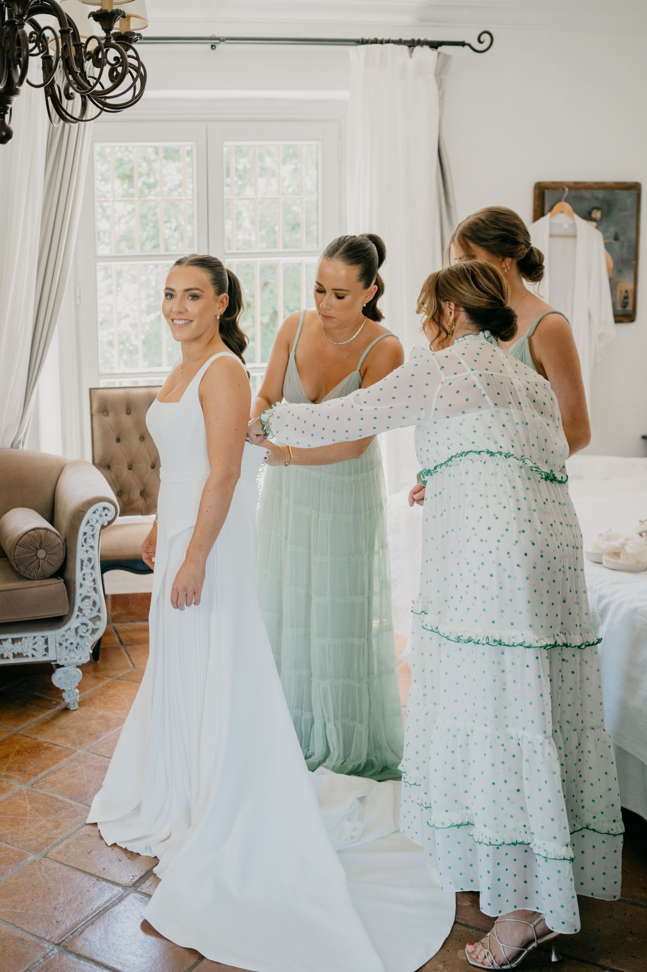 Wedding dress fitting moment as attendants help adjust the elegant white gown.