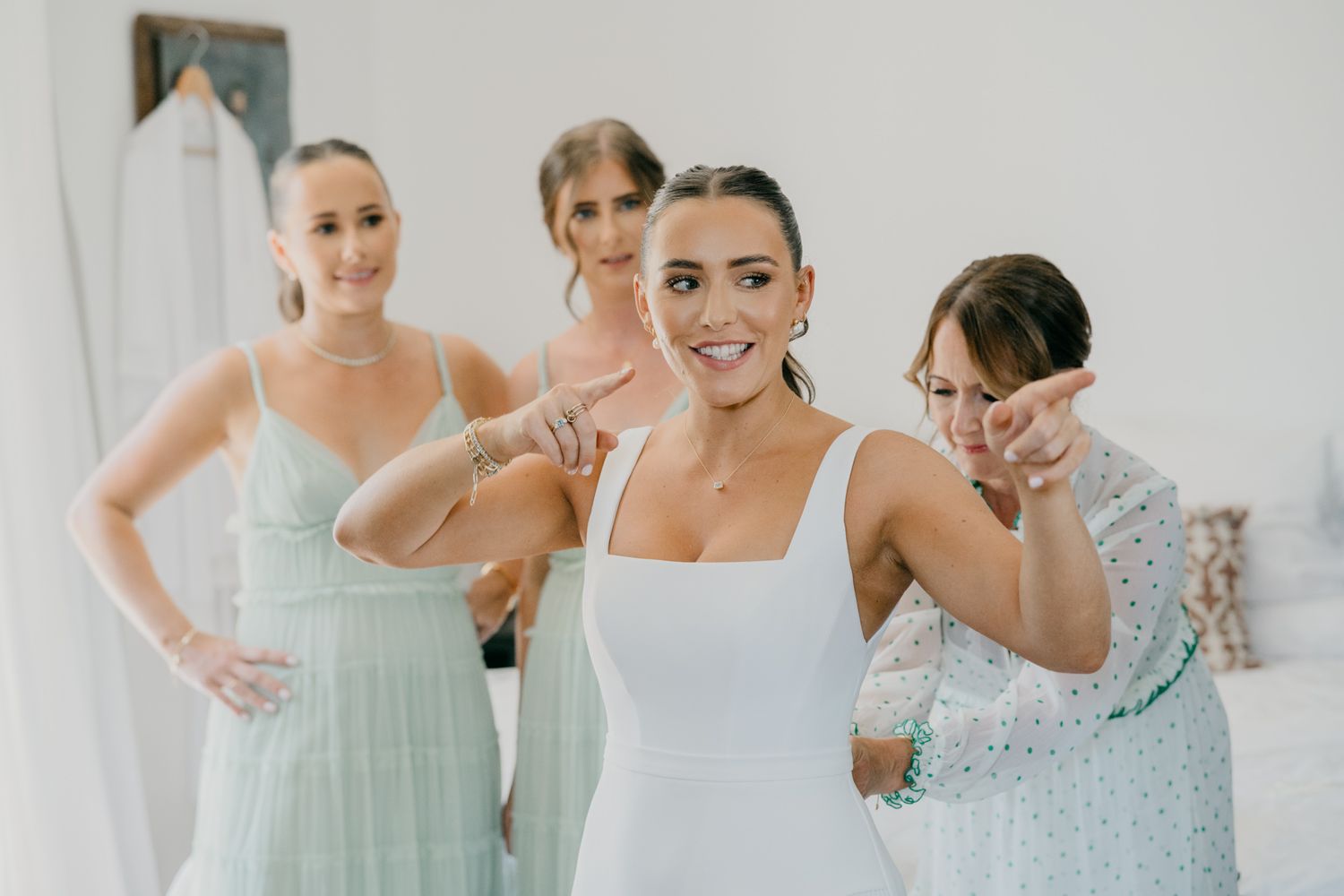 Joyful moment during wedding preparations as bridesmaids in mint dresses share laughs.