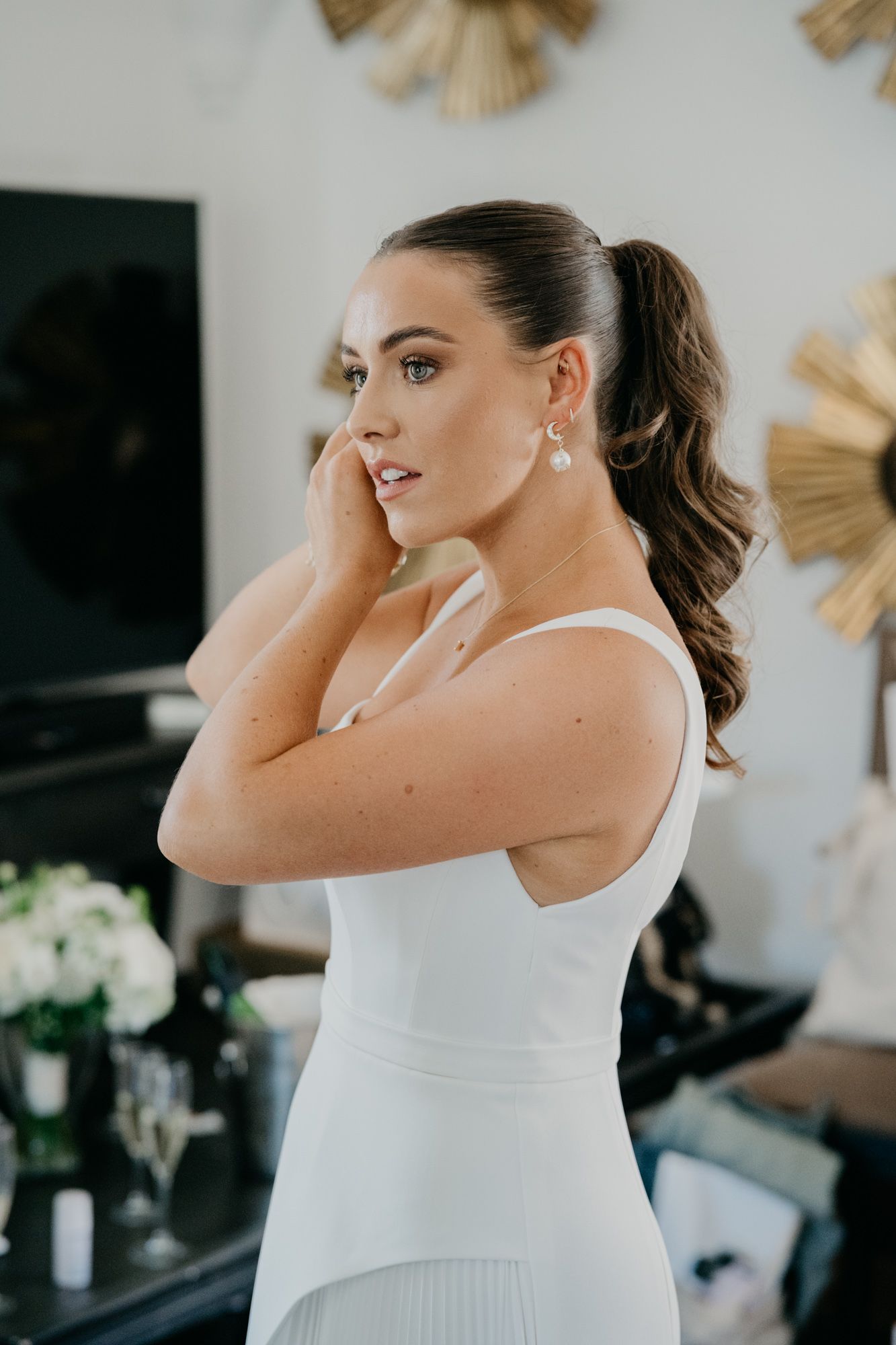 Side view of an elegant white wedding dress being worn during preparation.