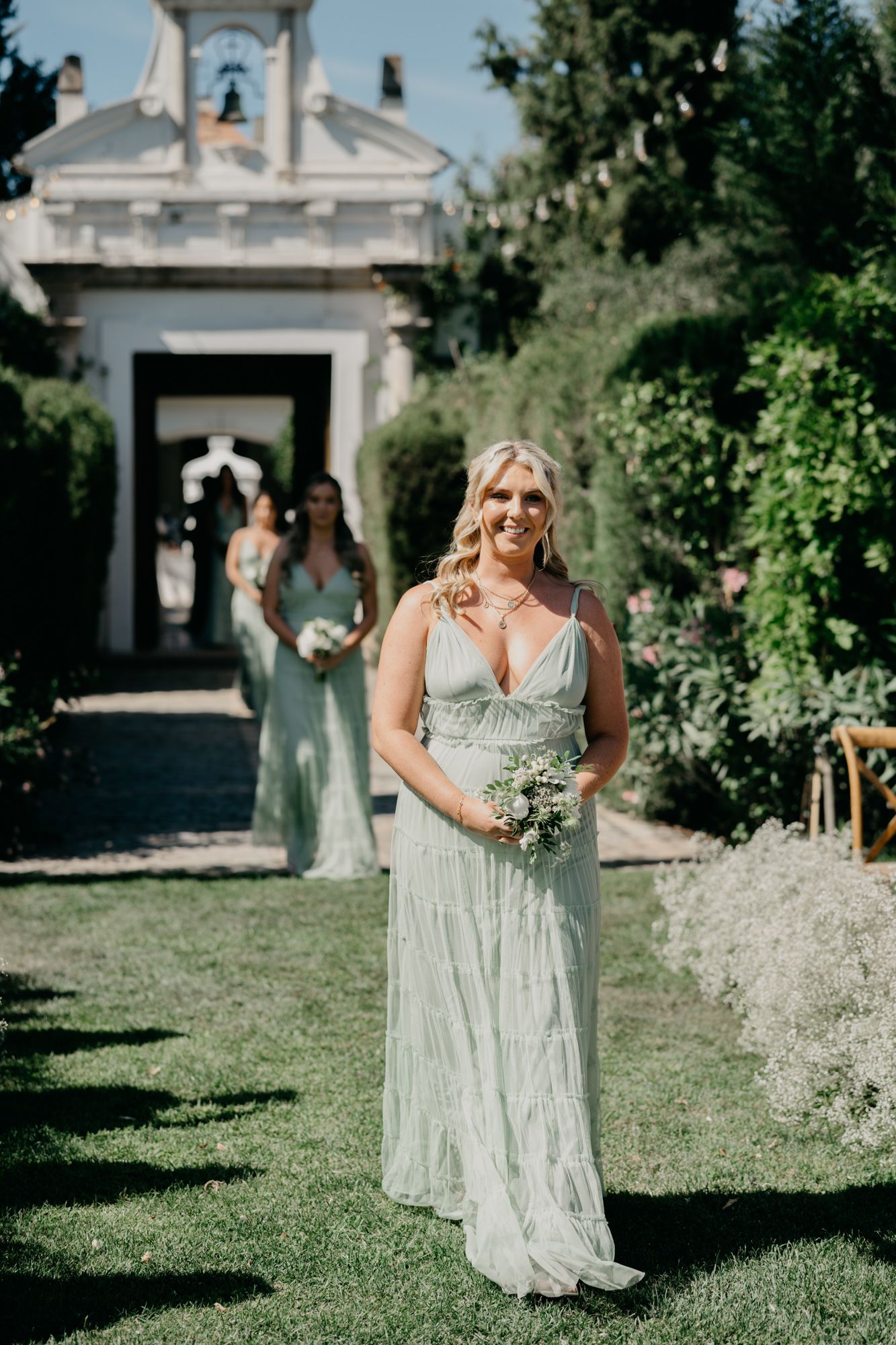 Elegant outdoor wedding at a historic chapel with lush garden surroundings and stone pathways.