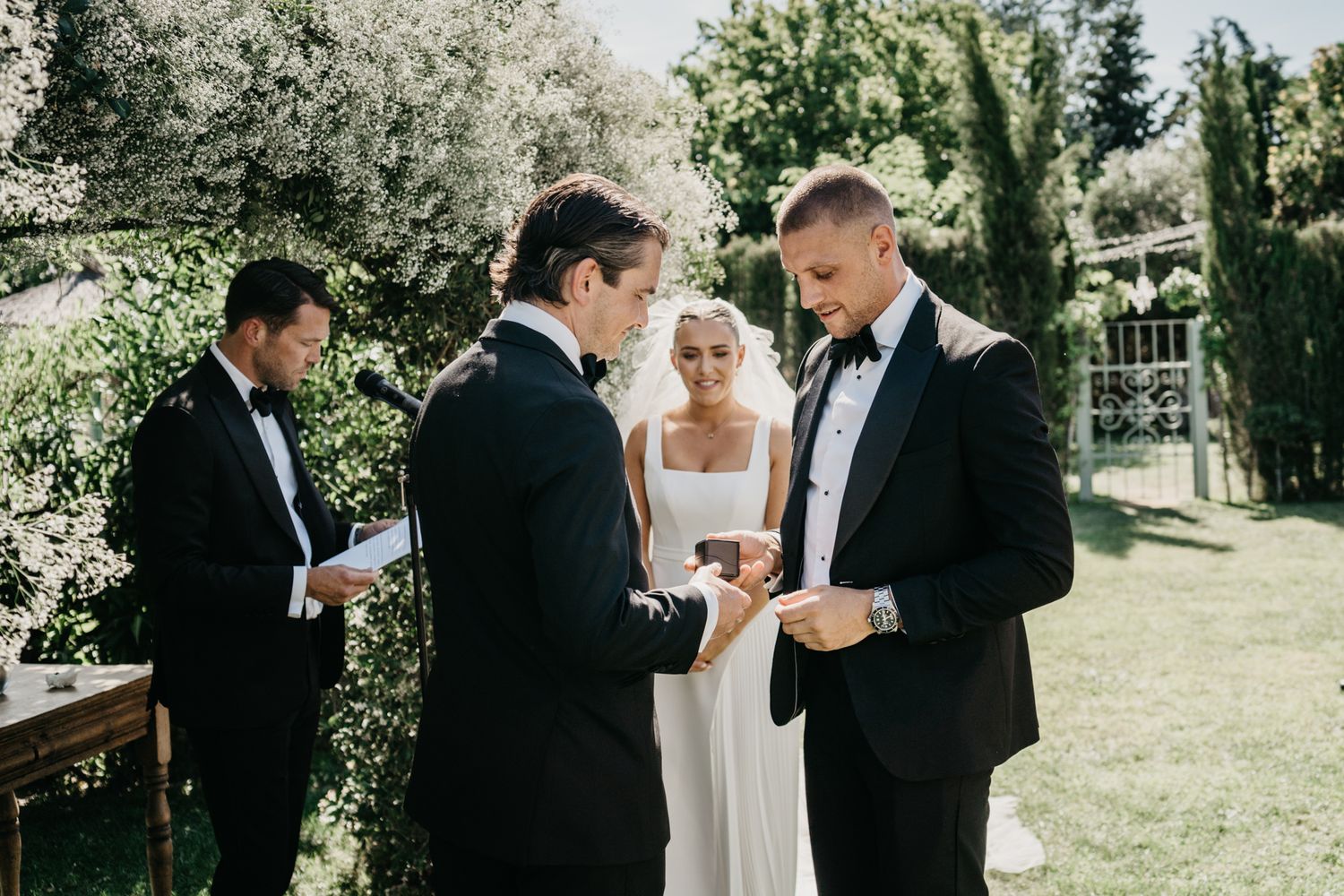 Ring exchange moment during intimate garden wedding ceremony.