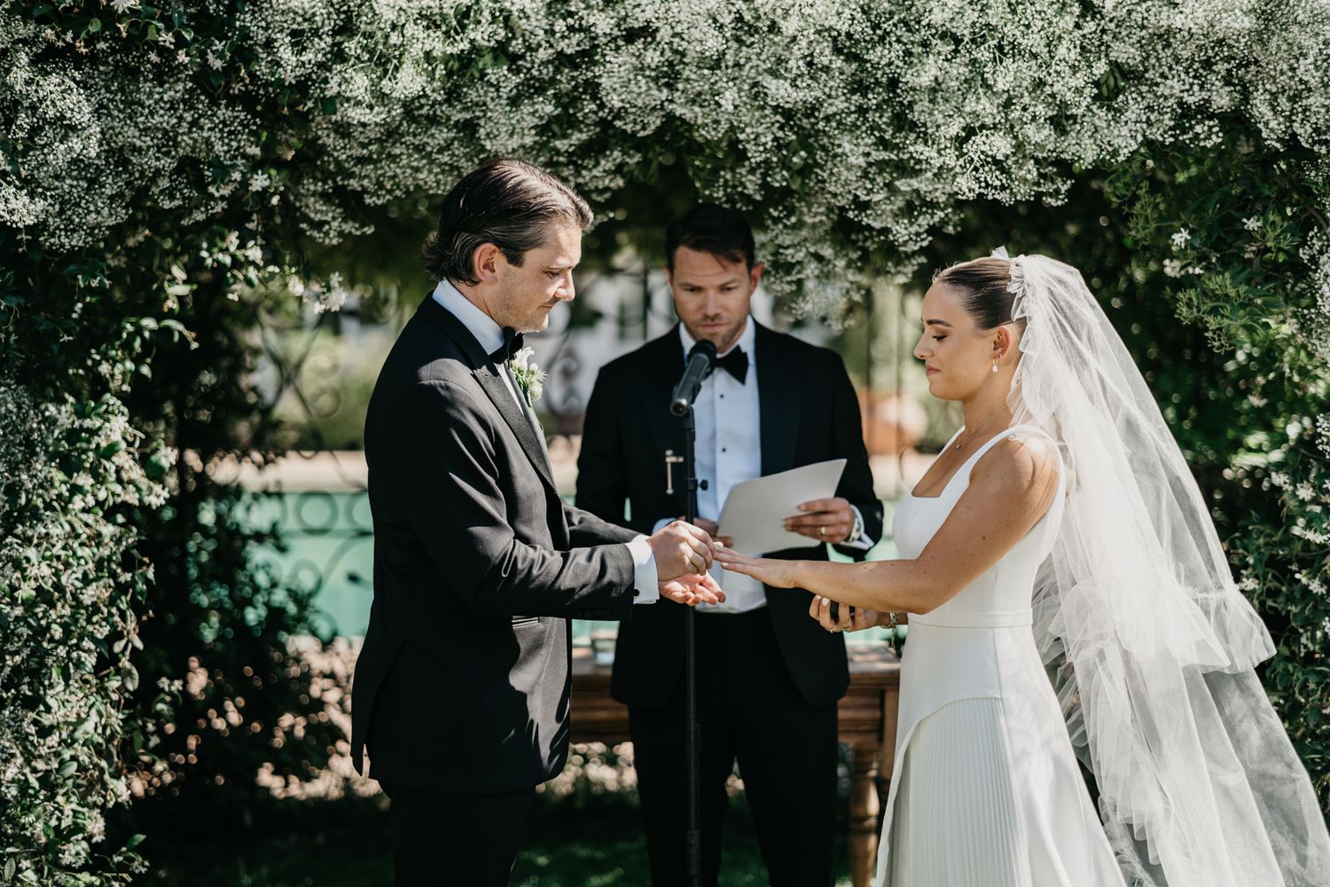 Wedding ceremony vow exchange in lush garden setting.