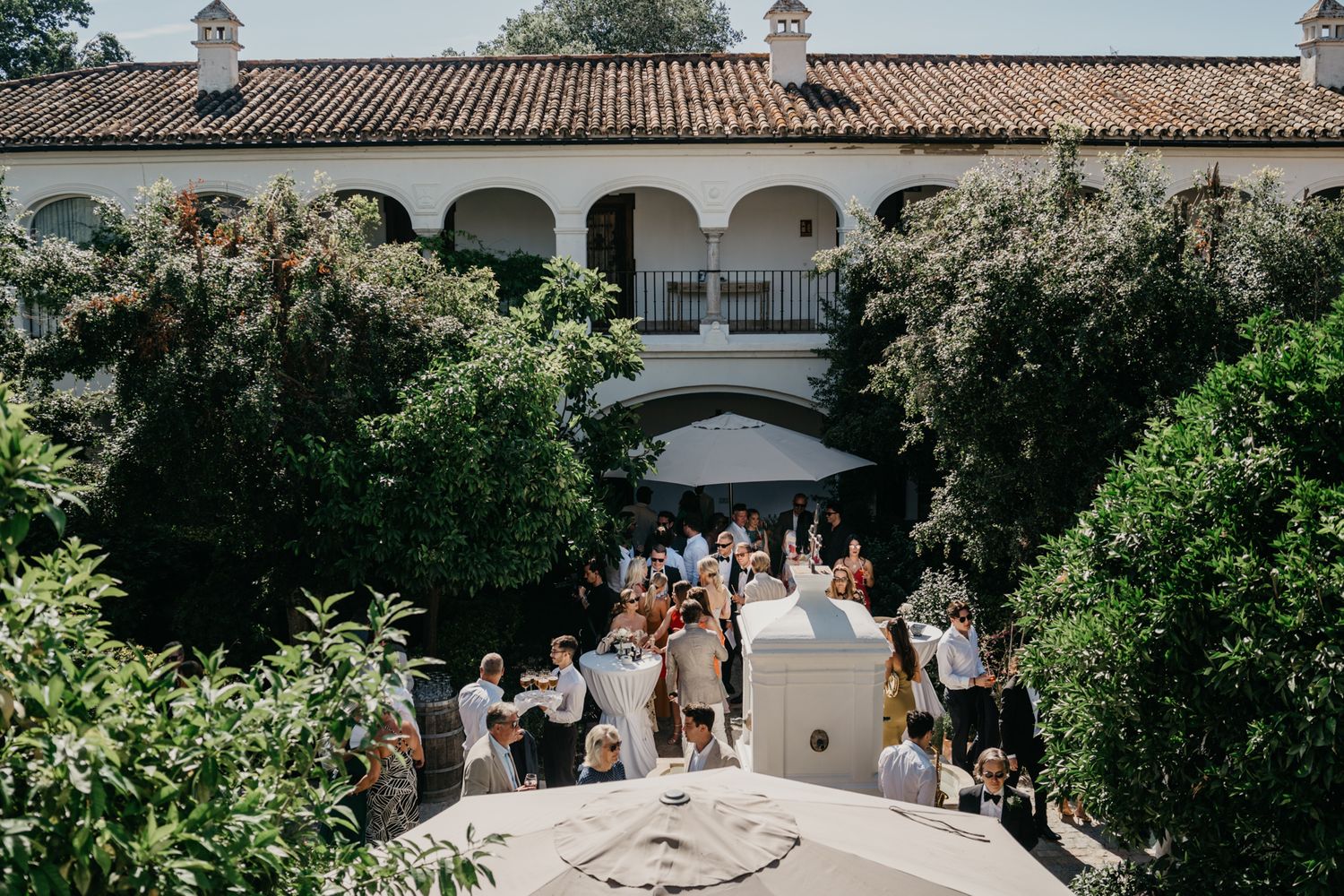 Spanish-style wedding venue with arched colonnade and gathered guests.