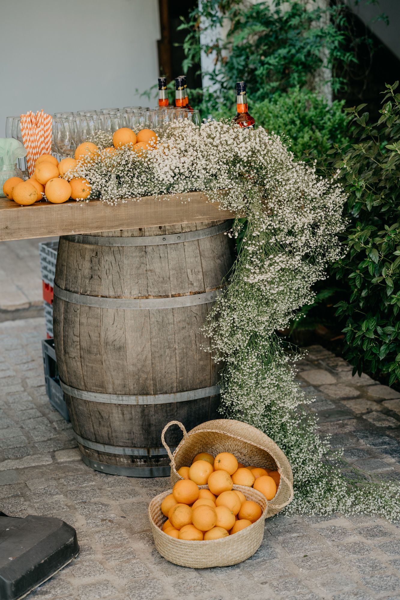 Rustic bar display with wooden barrels, fresh oranges and baby's breath floral arrangements.