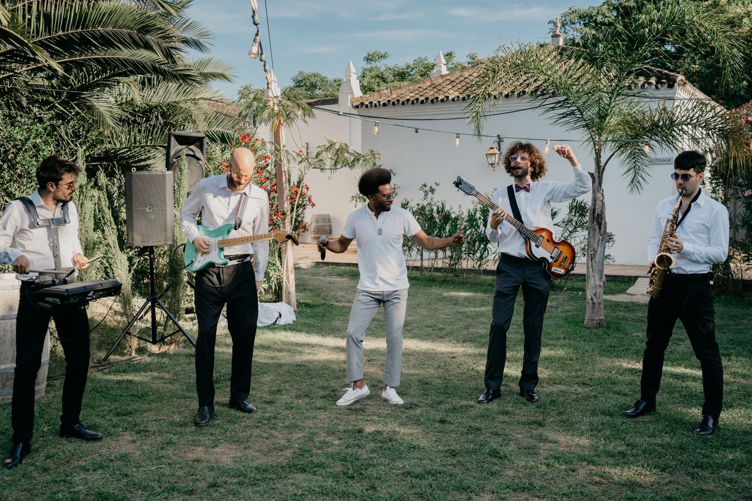 Live band performing in a tropical garden setting wearing formal attire.