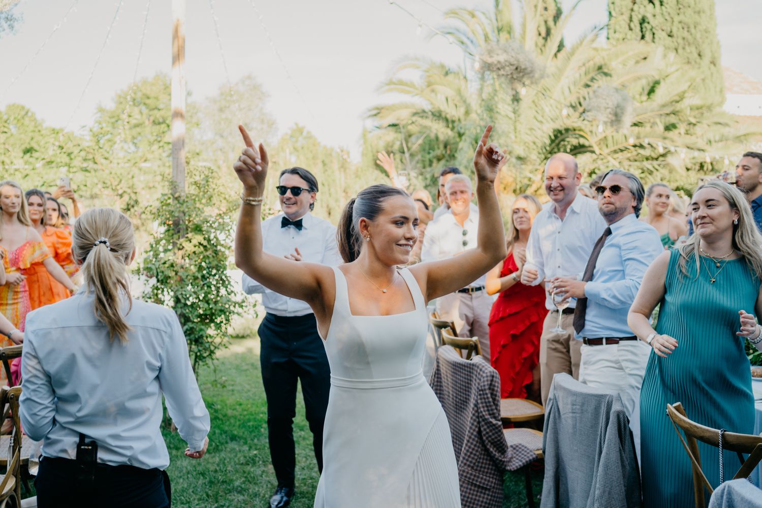 Joyful celebration at an outdoor wedding reception with guests dancing.