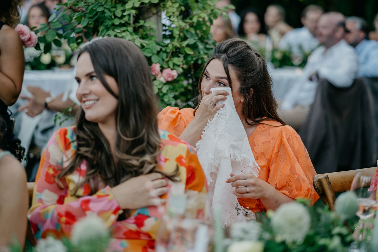 Wedding guests sharing joyful moments at outdoor reception with floral decorations.