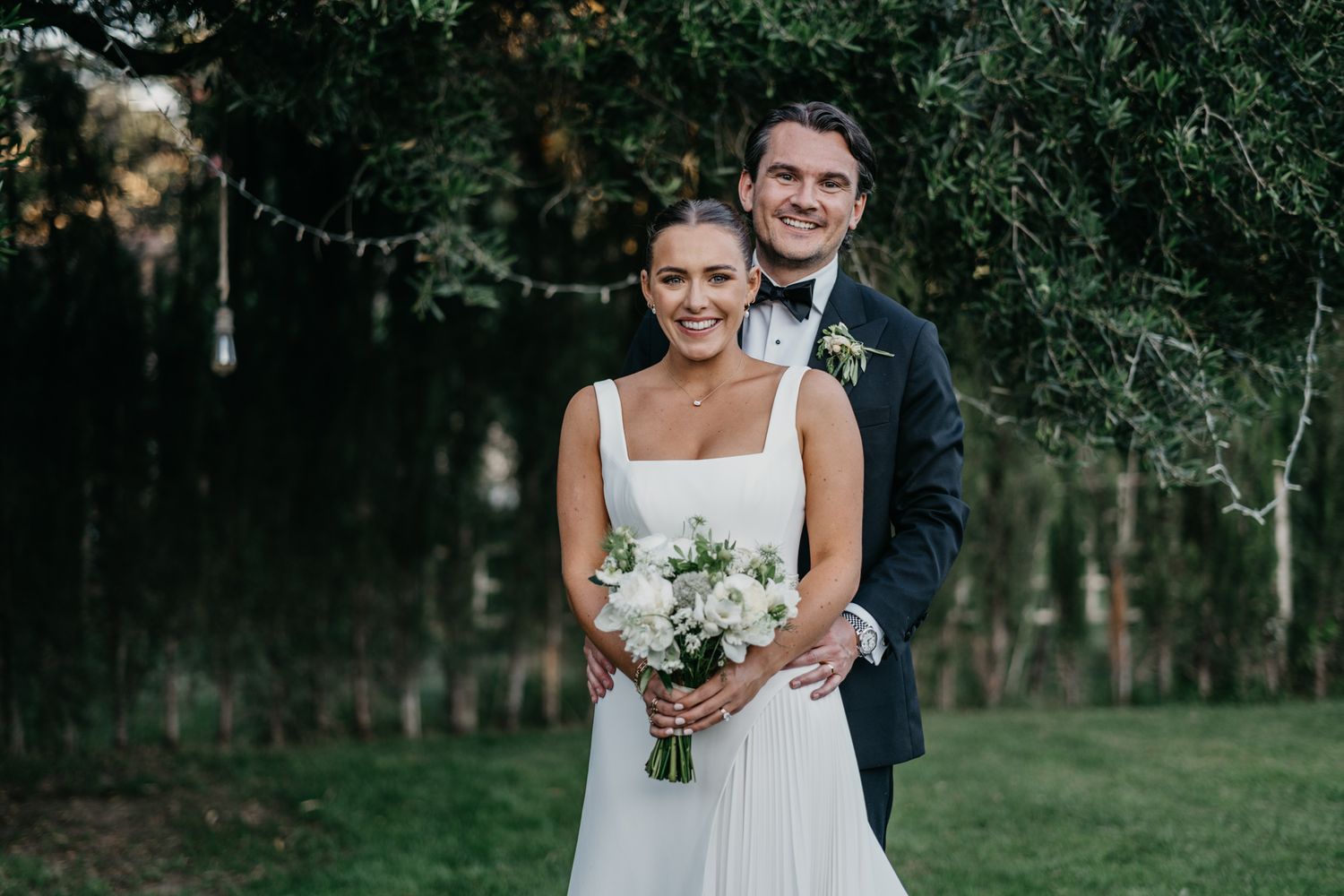 Elegant outdoor wedding portrait with couple amongst garden greenery.