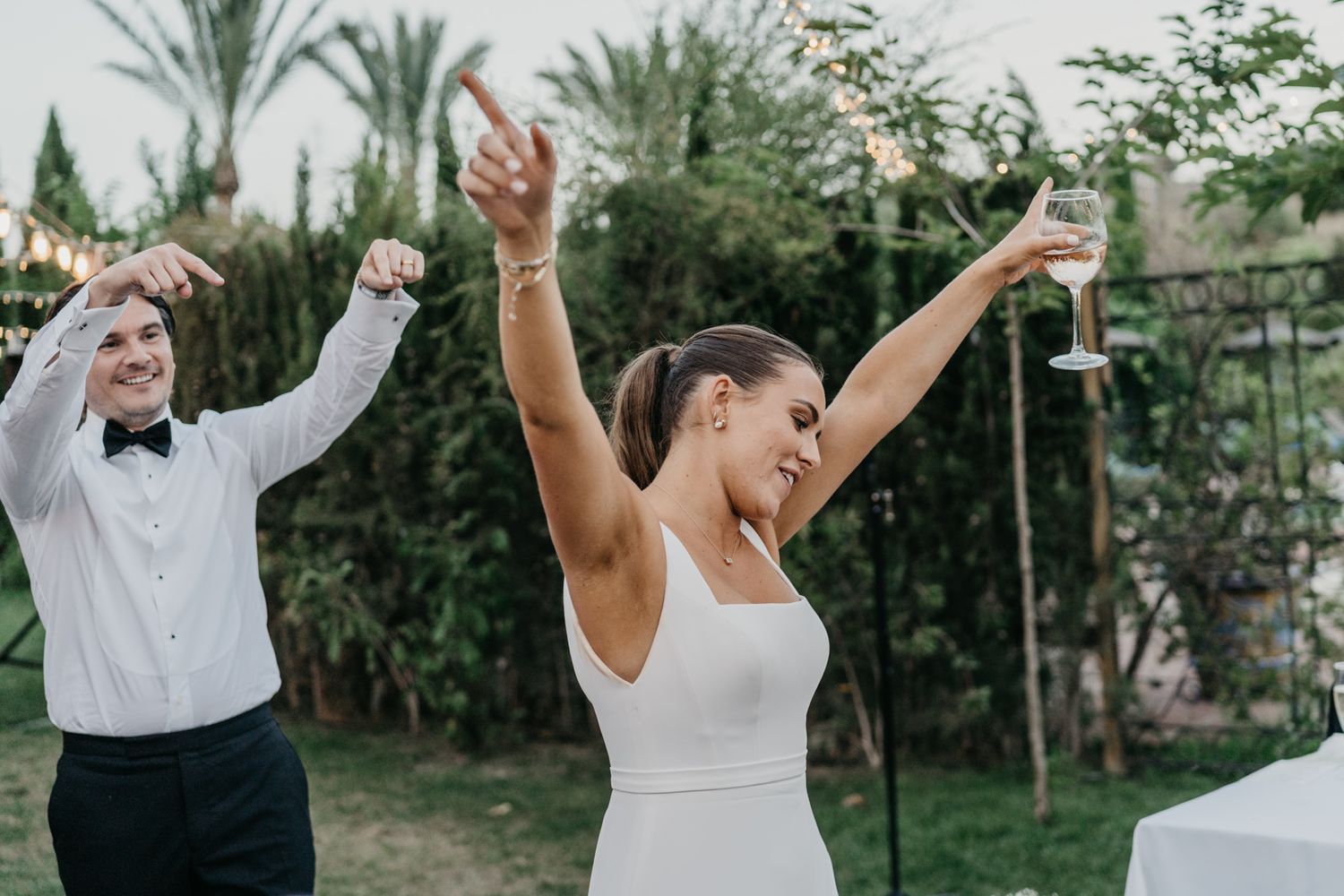Joyful celebration moment at outdoor wedding with raised arms and dancing.