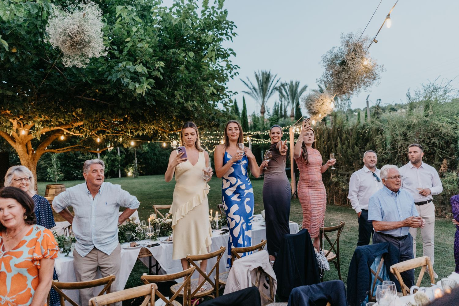 Guests enjoying an outdoor wedding reception with string lights and tropical garden ambiance.