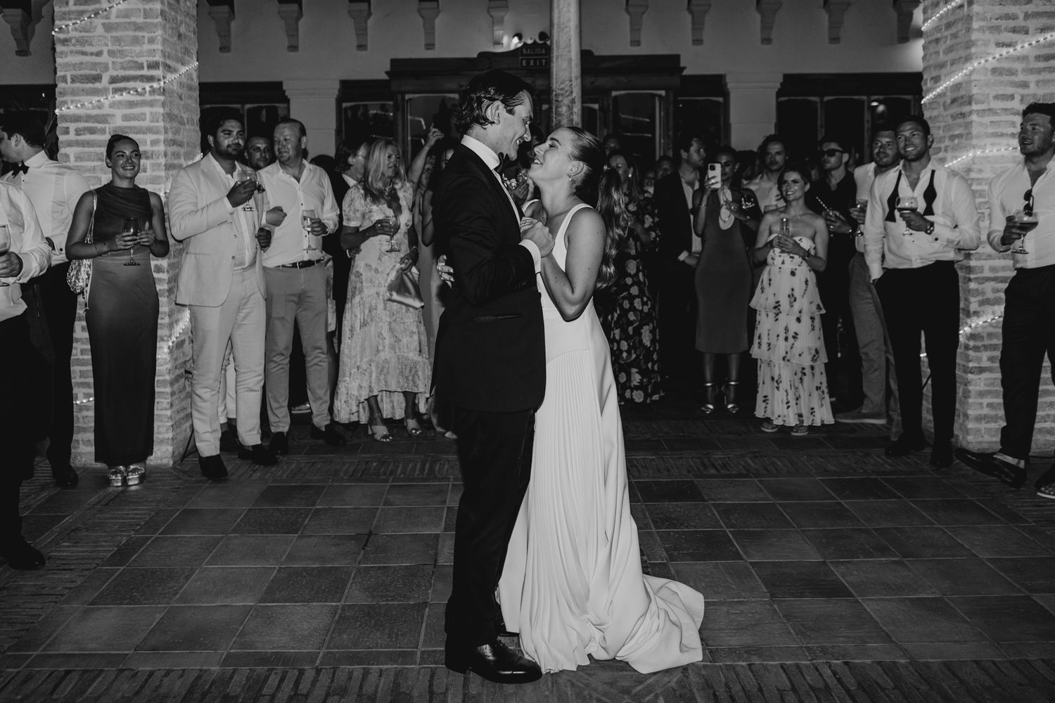 Black and white photo of newlyweds sharing their first dance at their wedding reception.