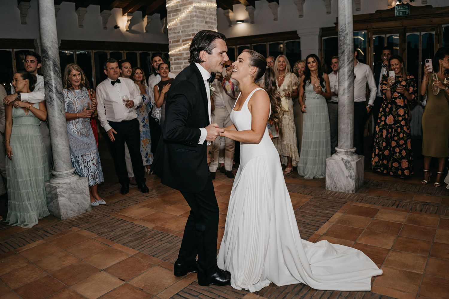 Couple shares a romantic dance moment on their wedding day surrounded by guests.