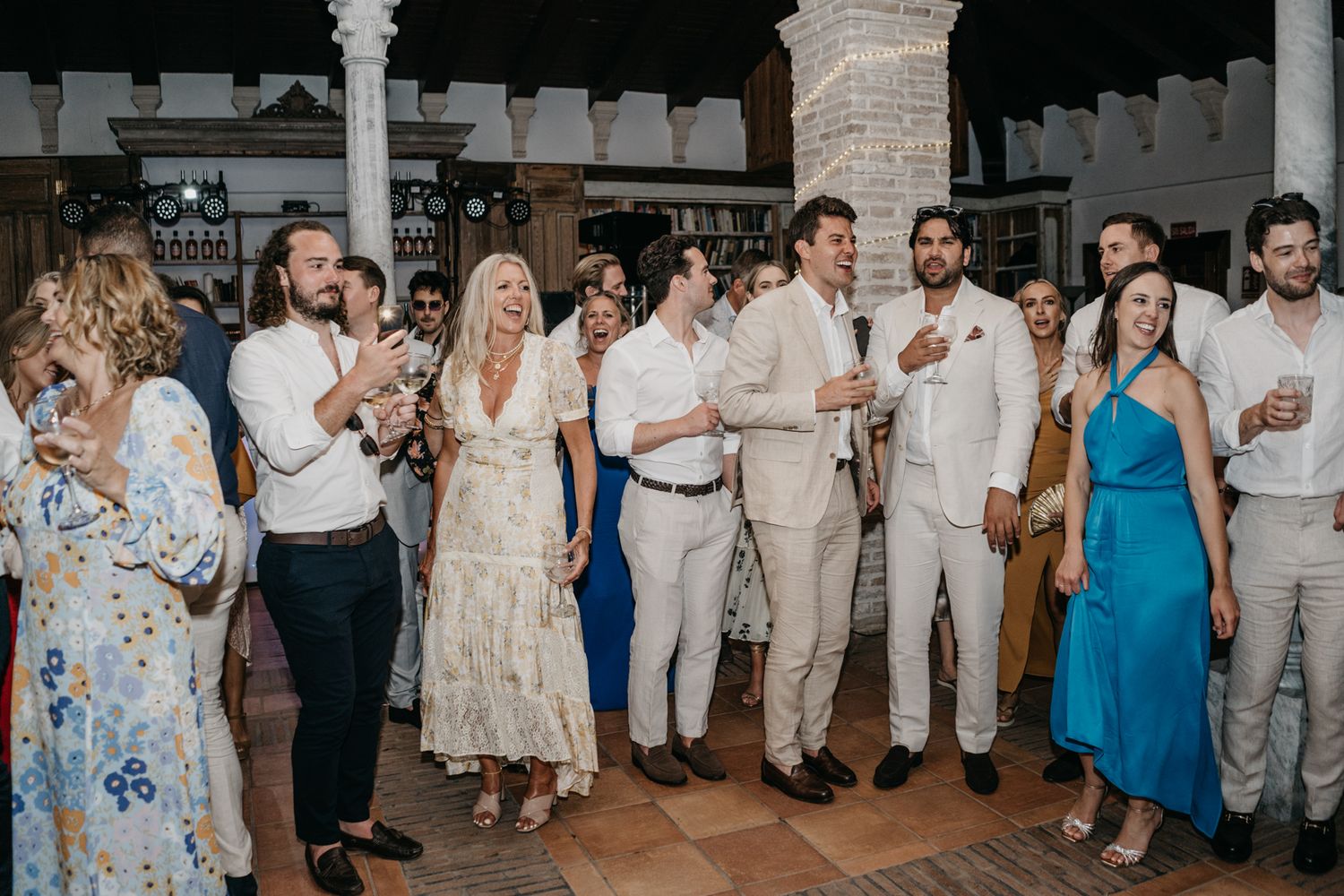 Wedding guests in light summer attire socialize during the reception.