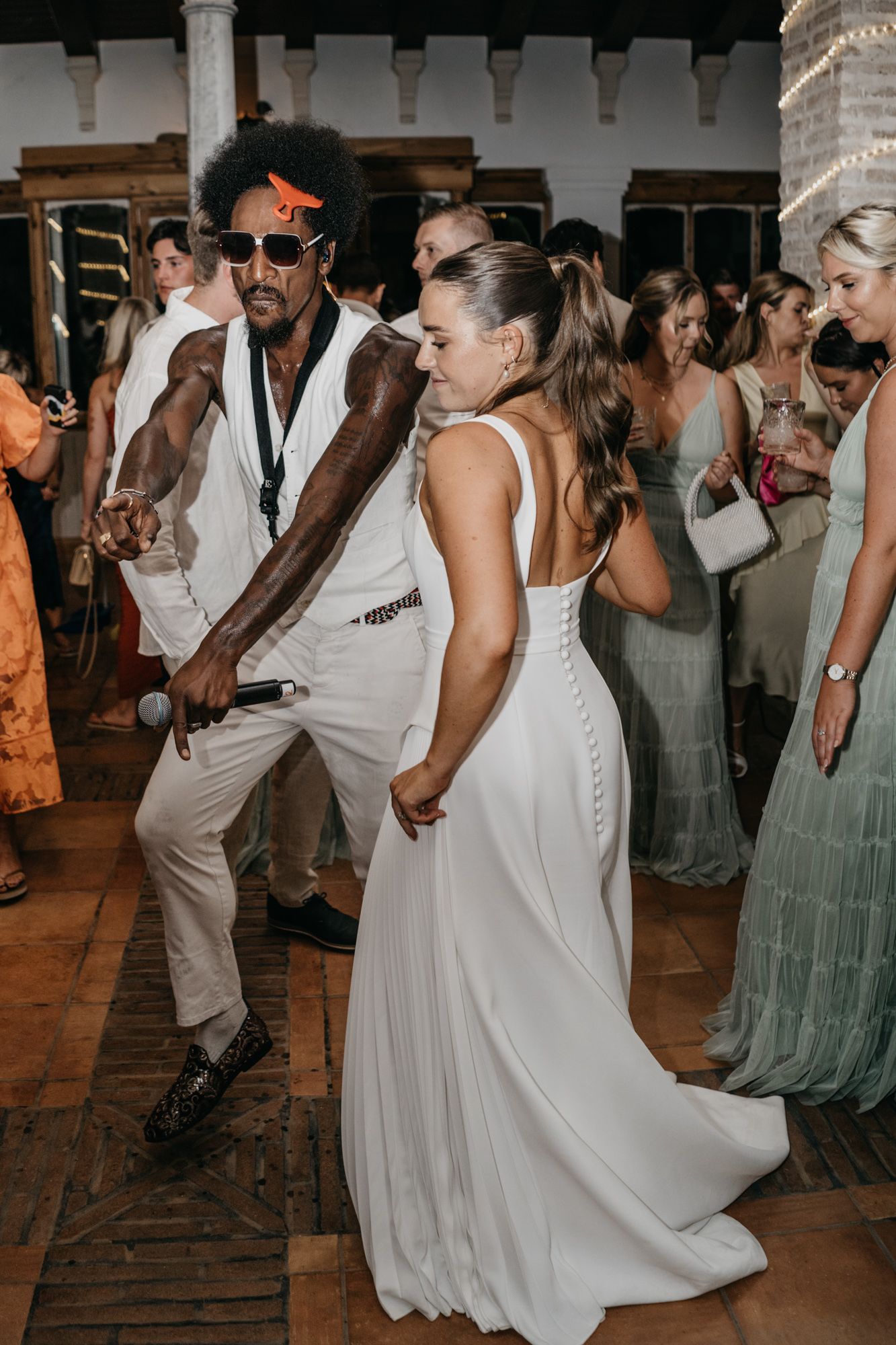 Wedding guests dance energetically at a lively reception party.