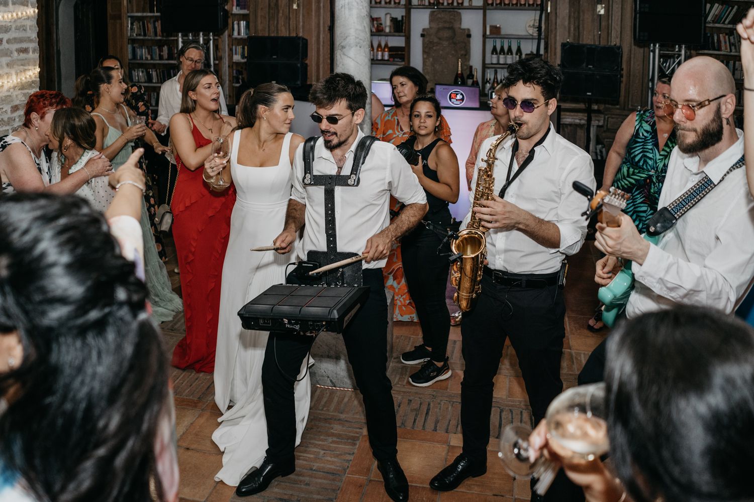 Wedding reception dance party with musicians and guests dancing in formal attire.