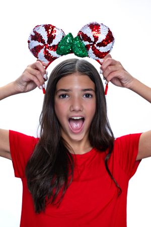 Excited person in red shirt holding peppermint-themed Disney ears headband modeling for Hug A Band.