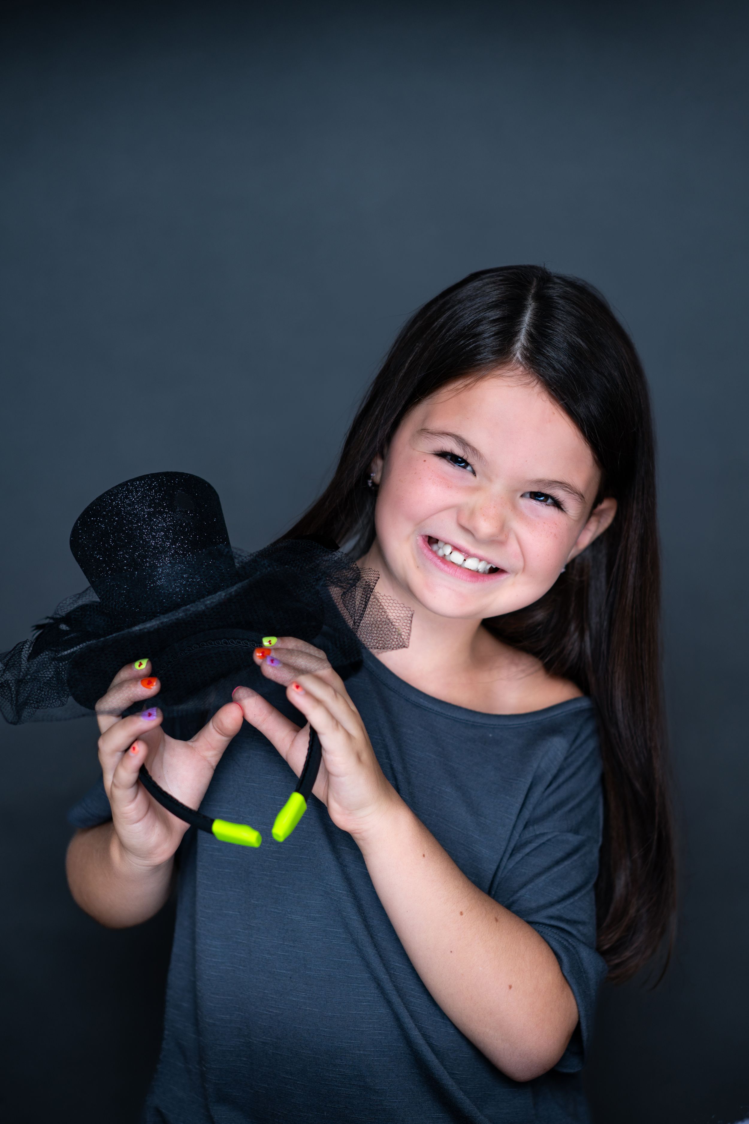 Young person in dark shirt holding black plush Mickey Mouse toy against dark background modeling for Hug A Band.
